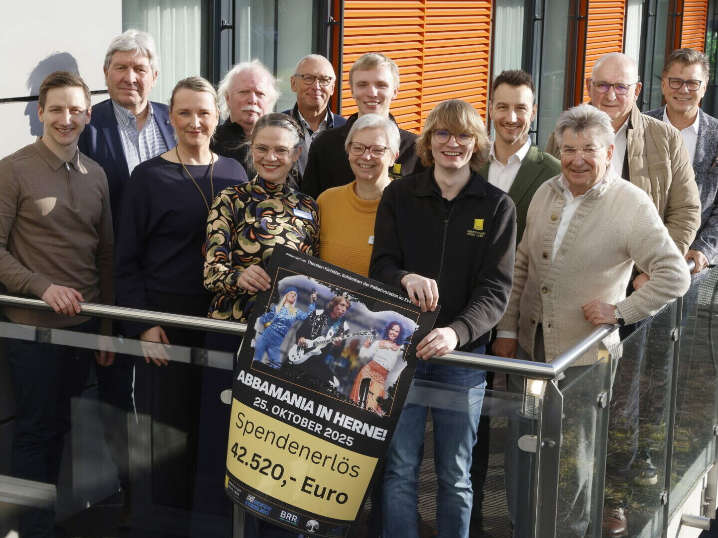 Menschen stehen auf einem Balkon und halten ein Plakat in der Hand. Darauf steht: Spendenerlöse 42.520 Euro.