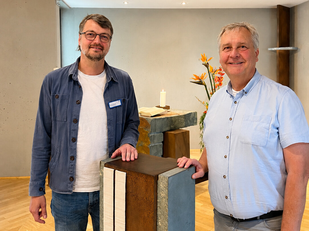 Zwei Männer stehen an einem Rednerpult in einem kirchlichen Raum.
